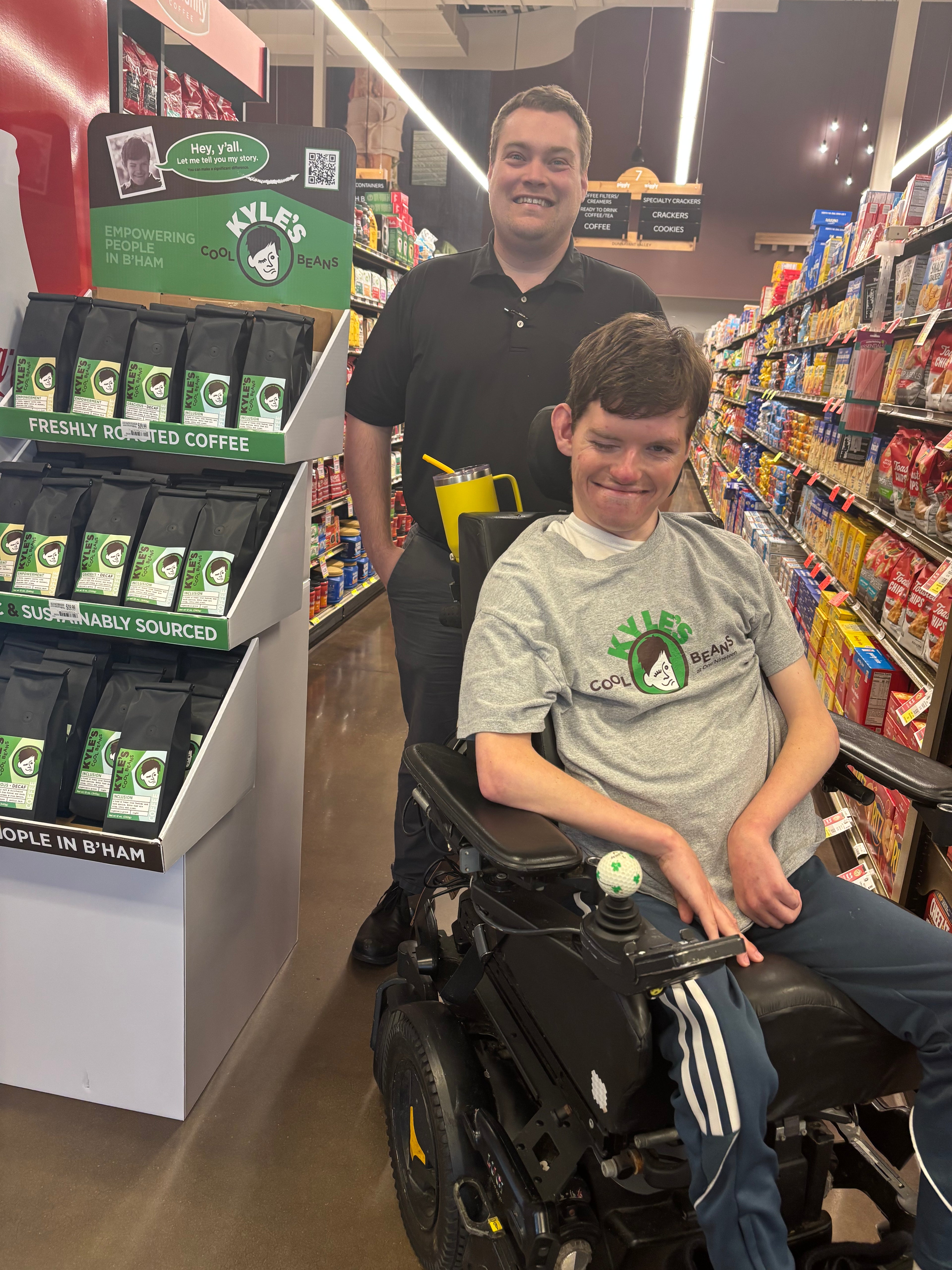 Kyle at Piggly Wiggly with an employee both are smiling and standing next to a display of Kyle’s Cool Beans Coffee!